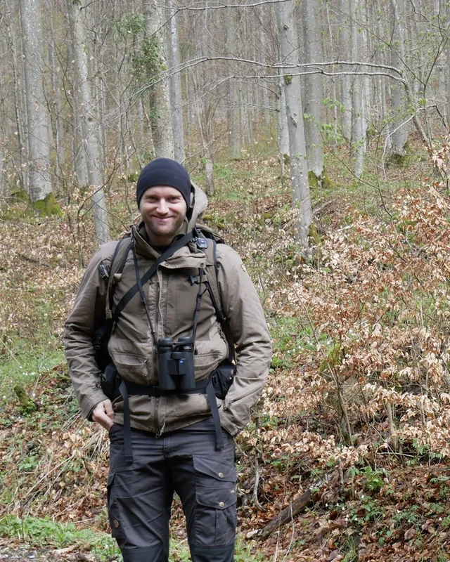 Andreas Kuhn with binoculars in a beech forest